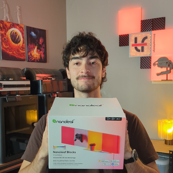 A man holding a box in a home office environment with warm ambient lighting.